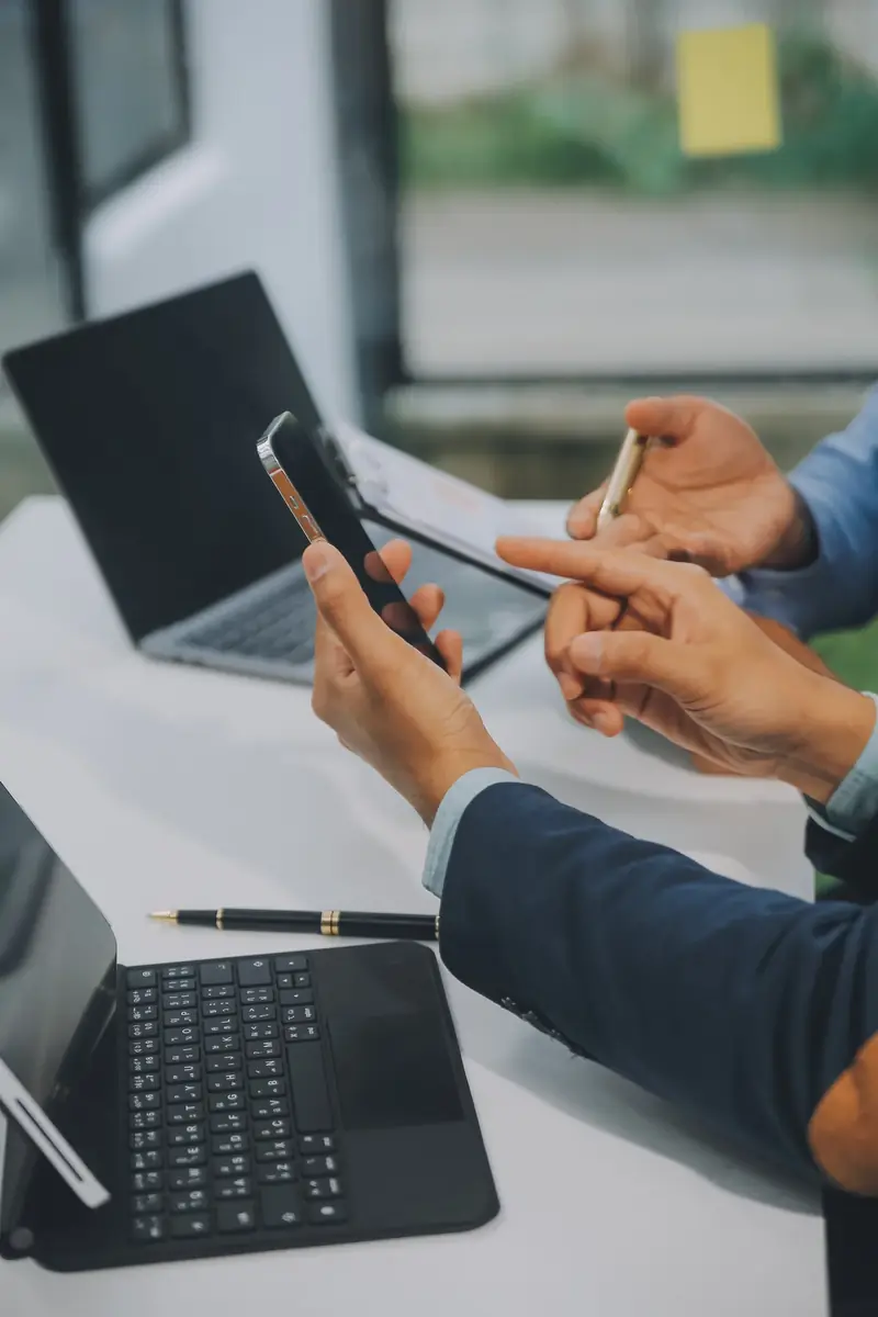 Two people reviewing something on a phone across an office desk.